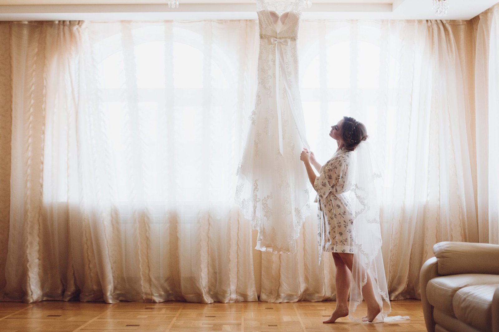 Beautiful bride walking to her luxury wedding dress by the window