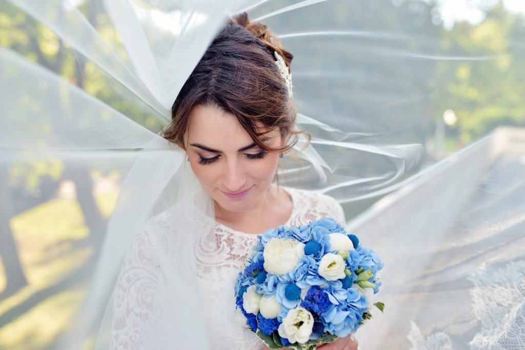 A bride in her gown with bouquet and lace veil